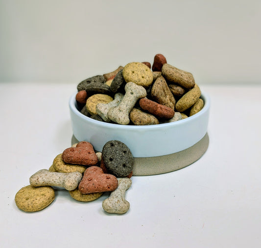 Assorted dog treats in a light blue bowl on a white surface